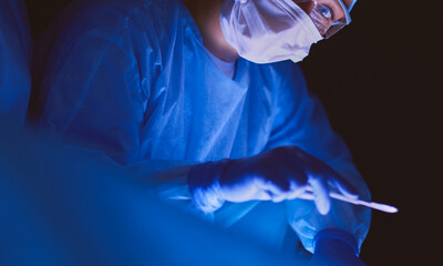 Doctors team in surgery in a dark background.