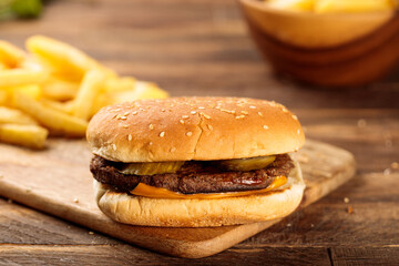 Beef Burger with fries served in a cutting board isolated on wooden table background side view of fastfood