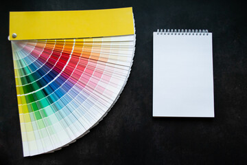 Paper fan paint swatch interior design, wall painting. Black background. White notebook, copy space