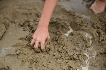 Child is playing in the beach, game with sand and hands, detail of the hands