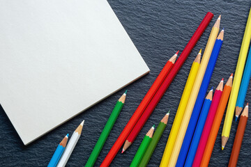 Colorful colored pencils and open sketchbook. Flat lay, free space for text or picture