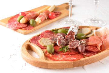 Charcuterie plate with different types of sausages - salami, bresaola, proscuitto served with crackers and olives. Menu background. Traditional italian antipasti on white table