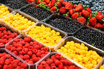 Colourful mix of different fresh berries at market. Raspberries, strawberries, blueberries and bilberries