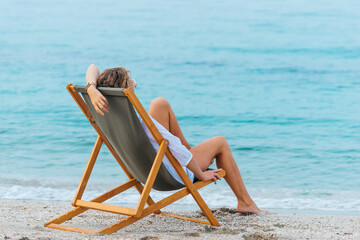 Girl sitting on a sun lounger by the sea