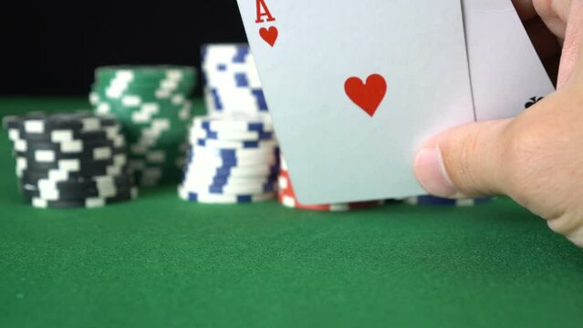 Poker game with a pair of aces betting all the poker chips. Close-up of a gambler hand is holding playing cards in poker club