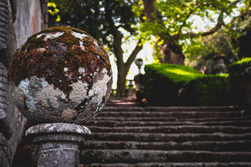 Mossy earth-looking spherical stone in a garden on top of a pillar. Villa Lante, Bagnaia, Italy