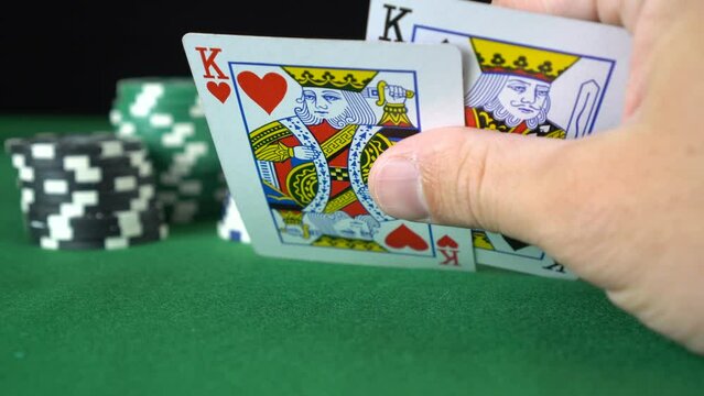 Poker game with a pair of kings betting all the poker chips. Close-up of a gambler hand is holding playing cards in poker club