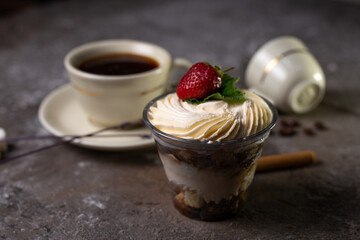 dessert in a glass with strawberries and a cup of tea