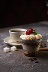 dessert in a glass with strawberries and a cup of tea