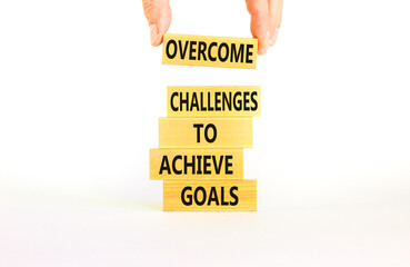 Overcome challenges to achieve goals symbol. Concept words Overcome challenges to achieve goals on wooden blocks on a beautiful white background. Businessman hand. Business goals concept. Copy space.