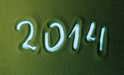 Hand drawing Year Number 2014 Symbol in the Green Sand. Male hand writes a number on the green sand...