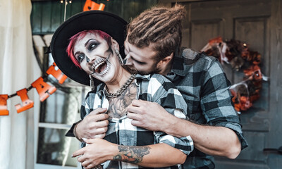 Scary love romantic family couple man,woman celebrating halloween.Terrifying black skull half-face makeup,witch costumes.Stylish images,jacket,hat.Fun at photoshoot,holiday party. Decorating of porch