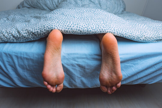 Woman feet under the blanket at night. Healthy skin and legs. 
