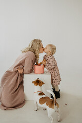 Mom with a little daughter in the studio eat a cake, hug and kiss. Girl's birthday.