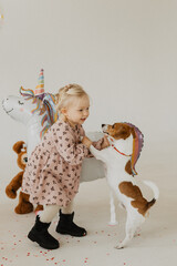 Little girl on her birthday. Little girl near the cake, balls. Little girl dances with a dog.
