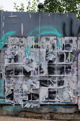Fence site with placed advertising posters, incomprehensible content