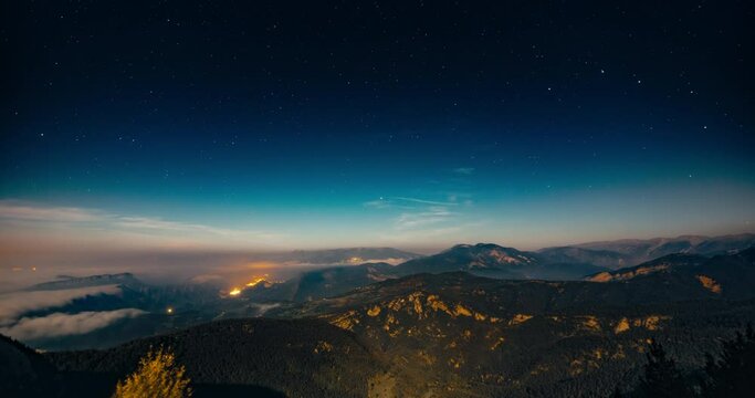 Beautiful mountain landscape timelapse at night with stars moving on sky panorama camera movement. Low clouds on mountain peaks on starlapse