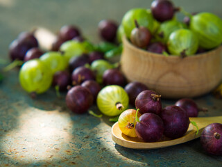 Gooseberries in a bowl on an old surface. leaves and berries of red and green gooseberries. Collect gooseberries. country style.