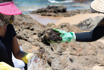 Volunteers clean up oil at beach. Using protective equipment.