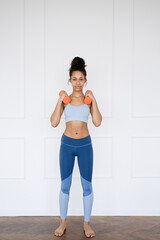 Fototapeta na wymiar Home Sport. Portrait African american woman exercising with dumbbells and enjoying fitness and healthy lifestyle