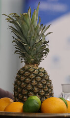Pineapple surrounded by citrus fruits: oranges and limes on a tray