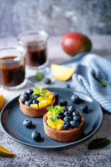 Chocolate tartlets with chocolate cream filling and mango fruit with blueberries
