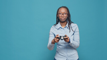 African american woman playing video games with controller, using tv console to have fun with gameplay and online gaming competition. Holding joystick to play action games on camera.