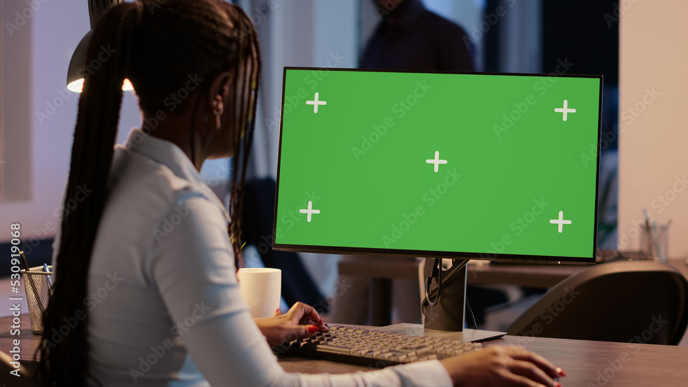 Poster company worker analyzing greenscreen display on monitor, looking at isolated screen in business offi