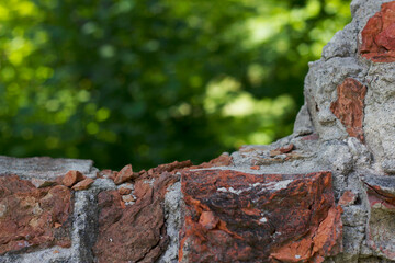 destroyed ancient brick wall with unfocused green nature background