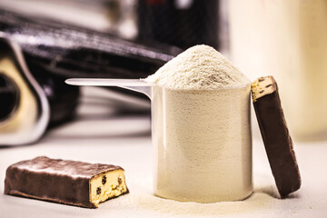 spoons with Creatine, whey and casein, amino acid pills, food supplements and protein bar for physical exercises, gym in the background, muscle mass gain