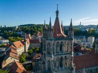 Fototapeta premium Lausanne, Switzerland, August 22nd 2022. Aerial drone shot of Lausanne cathedral, chateau St. Maire, and other buildings of the old city centre at sunrise.
