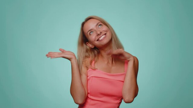Funny joyful sincere adult woman 20s in crop top making playful silly facial expressions and grimacing, fooling around showing tongue. Young lovely pretty girl isolated alone on blue wall background