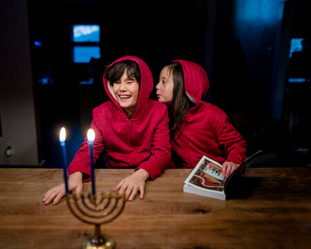 Two happy children sit at table with Hannukah candles