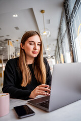 young girl in a cafe sitting at a laptop