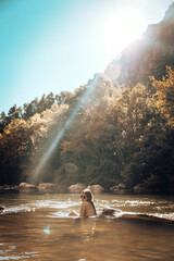 Naked girl bathing in a river surrounded by trees during sunset