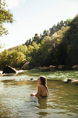 Fototapeta premium Naked girl bathing in a river surrounded by trees during sunset