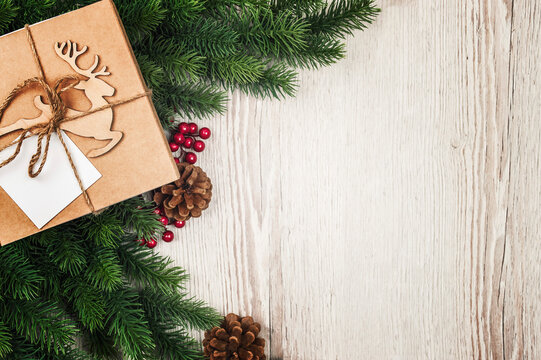 Christmas Fir tree branches, pine cones and gift on wooden rustic background. Banner, corner,  copy space.