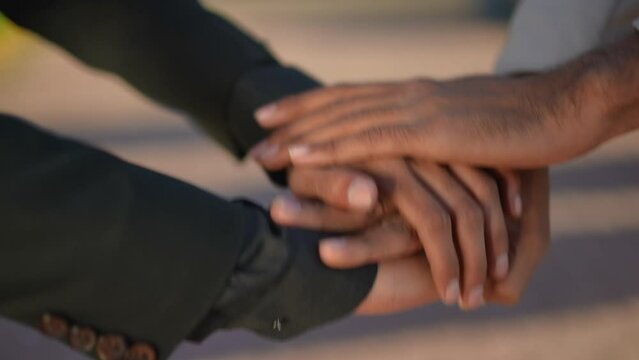 Close-up handstack in slow motion of two  unrecognizable men outdoors. Young confident friends stacking hands on city street. 
