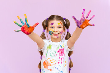 A little girl painted with multicolored paints will playfully have to create on a pink isolated background. Development of children's creativity for schoolchildren.