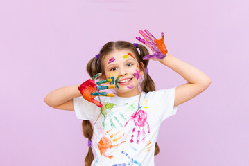 A little girl painted with multicolored paints will playfully have to create on a pink isolated...