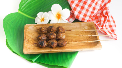 Bakso bakar is Indonesian grilled meatballs served on wooden plate