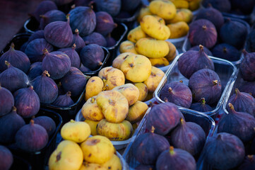 Fig fruits of different varieties on the counter of the farmers market in the evening sunlight....