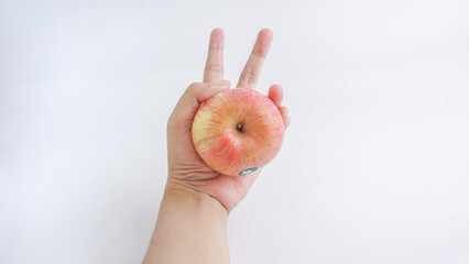 Female hand holding pink fuji apple isolated on white background.