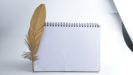 School notebook with gold feather on white background