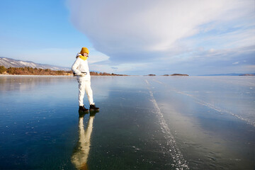 Portrait of a smiling athlete with figure skates on a frozen lake Baikal on a sunny winter day. Active recreation, unity with nature, outdoor sports, natural background.