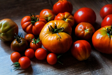 Irregular organic tomatoes of different sizes and textures, but very red.
