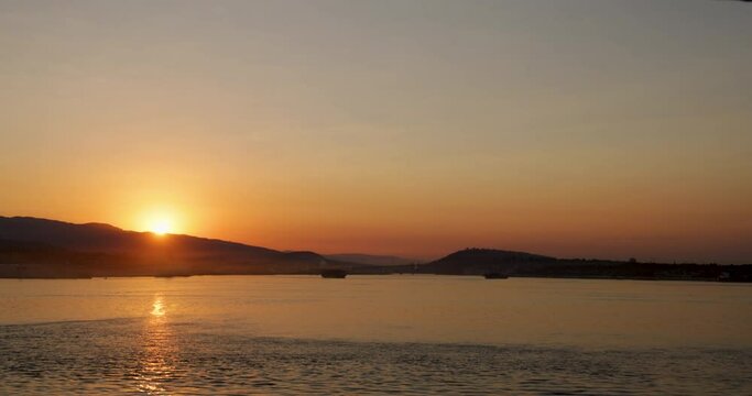 Brilliant sunrise over the harbor at Vancouver, Canada. Beautiful golden reflections shine across the calm rippling waters of the harbor as the sun just peeks over the hill at break of day.