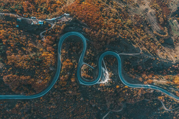 aerial photography of curved road on autumn, beautiful curved pass with vehicles and colorful autumn nature colors on trees with sunset light