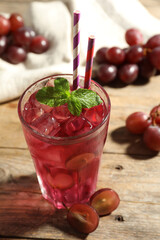 Delicious grape soda water with mint and berries on wooden table. Refreshing drink