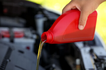 Man pouring motor oil from red container, closeup